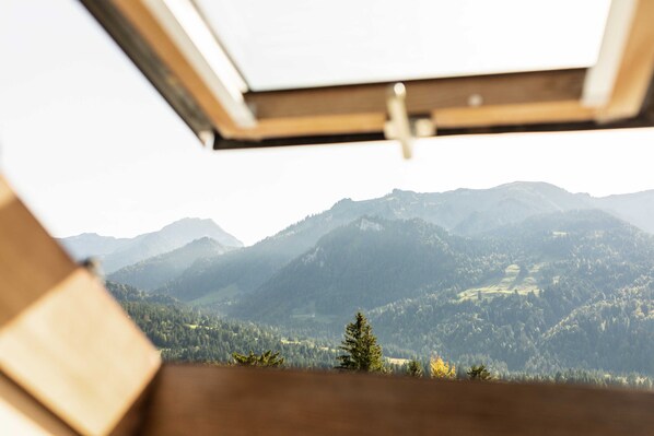 A mountain landscape through a window with a wooden frame.