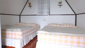 A room with two beds, each with a checkered bedspread, a window with patterned curtains, and two wall-mounted shelves with flowers. - Ukrist Farm Hill Resort (Thoeng)