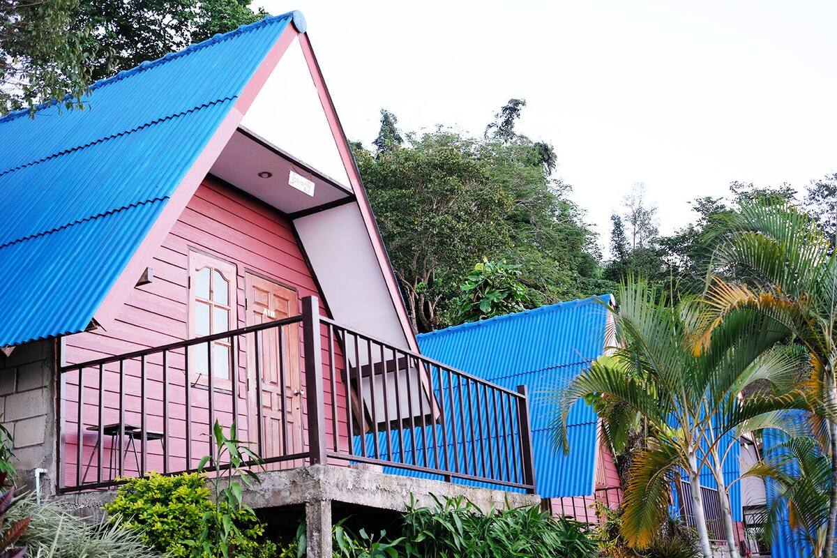 A pink building with a blue roof and a balcony with metal railings.