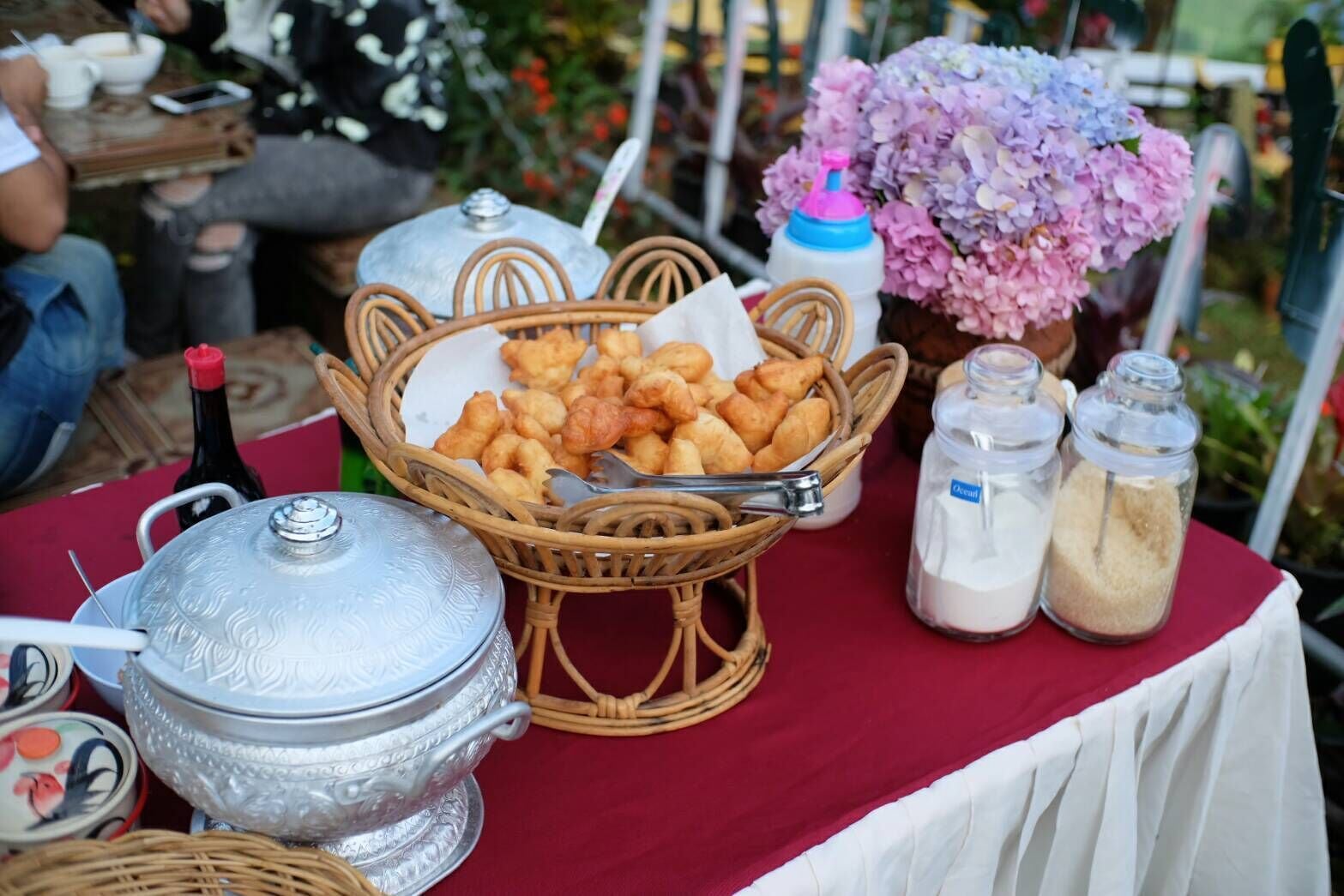 Une table de buffet avec un panier en osier rempli de pâtisseries, un plat de service en argent et deux salières.