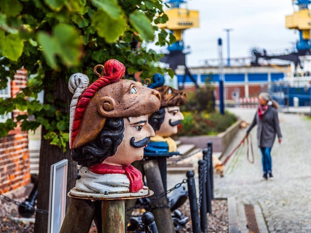 A row of decorative statues with a cobblestone path and a person walking in the background.