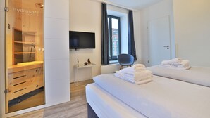 Une chambre d’hôtel avec deux lits, une télévision, un bureau, une chaise et une armoire en bois.