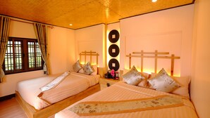 Hotellihuone, jossa on kaksi sänkyä, puiset päätylevyt, suuri ikkuna verhoilla ja seinään kiinnitetty valaisin.