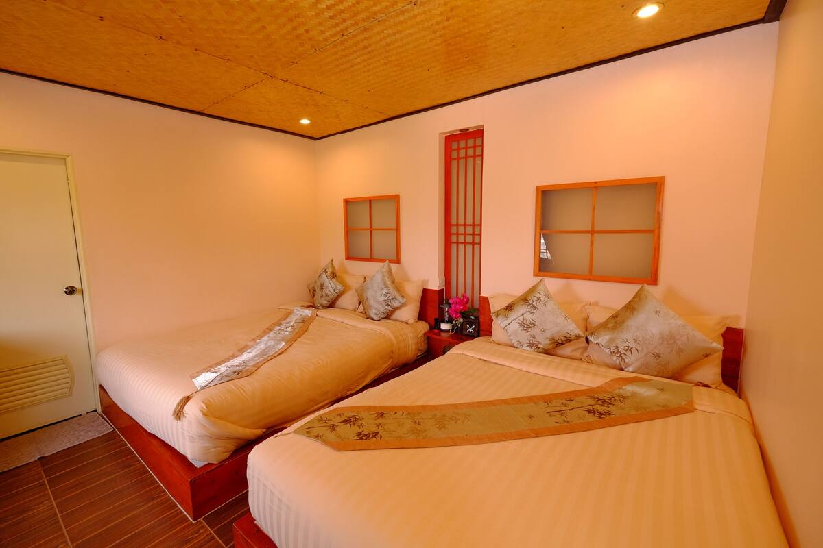 Habitación de hotel con dos camas, suelo de madera y una pared de estilo tradicional con una puerta roja.