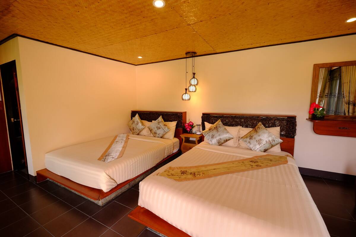 Habitación de hotel con dos camas y cabeceros de madera, con iluminación empotrada en el techo.