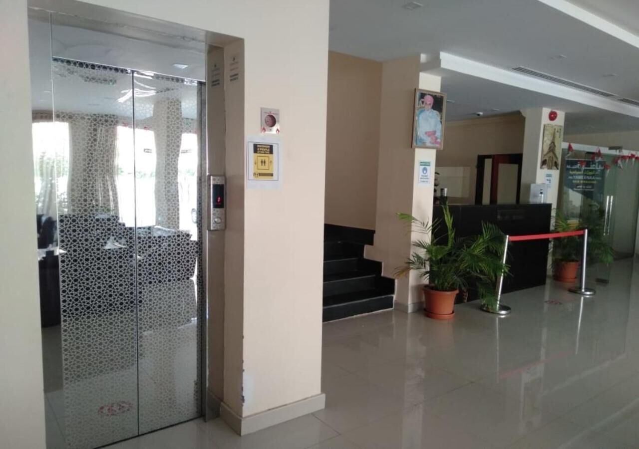 A reception area with a glass door, a reception desk, and potted plants.