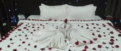 A bed with rose petals and a swan-shaped pillow, a 'HAPPY BIRTHDAY' banner, and a phone on the side.