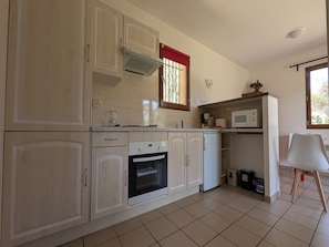 A kitchen with a built-in oven, microwave, and a window with a red curtain.