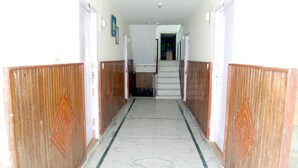 A hallway with wooden paneling on both sides, a tiled floor, and a staircase leading to an upper level. - Hotel Goher (Dalhousie)