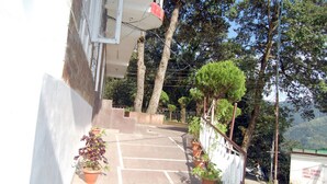 A parking area with potted plants and a white fence. - Hotel Goher (Dalhousie)