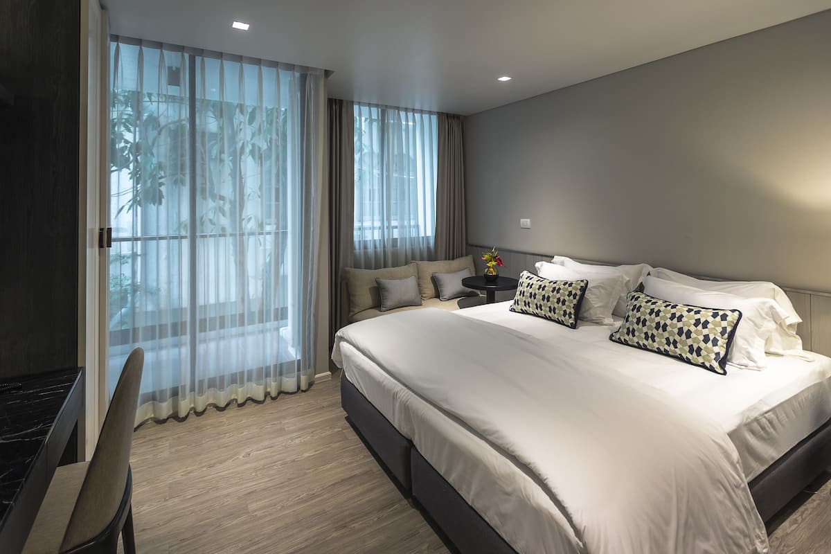 Une chambre d’hôtel moderne, dotée d’un grand lit, d’un bureau et d’une chaise.