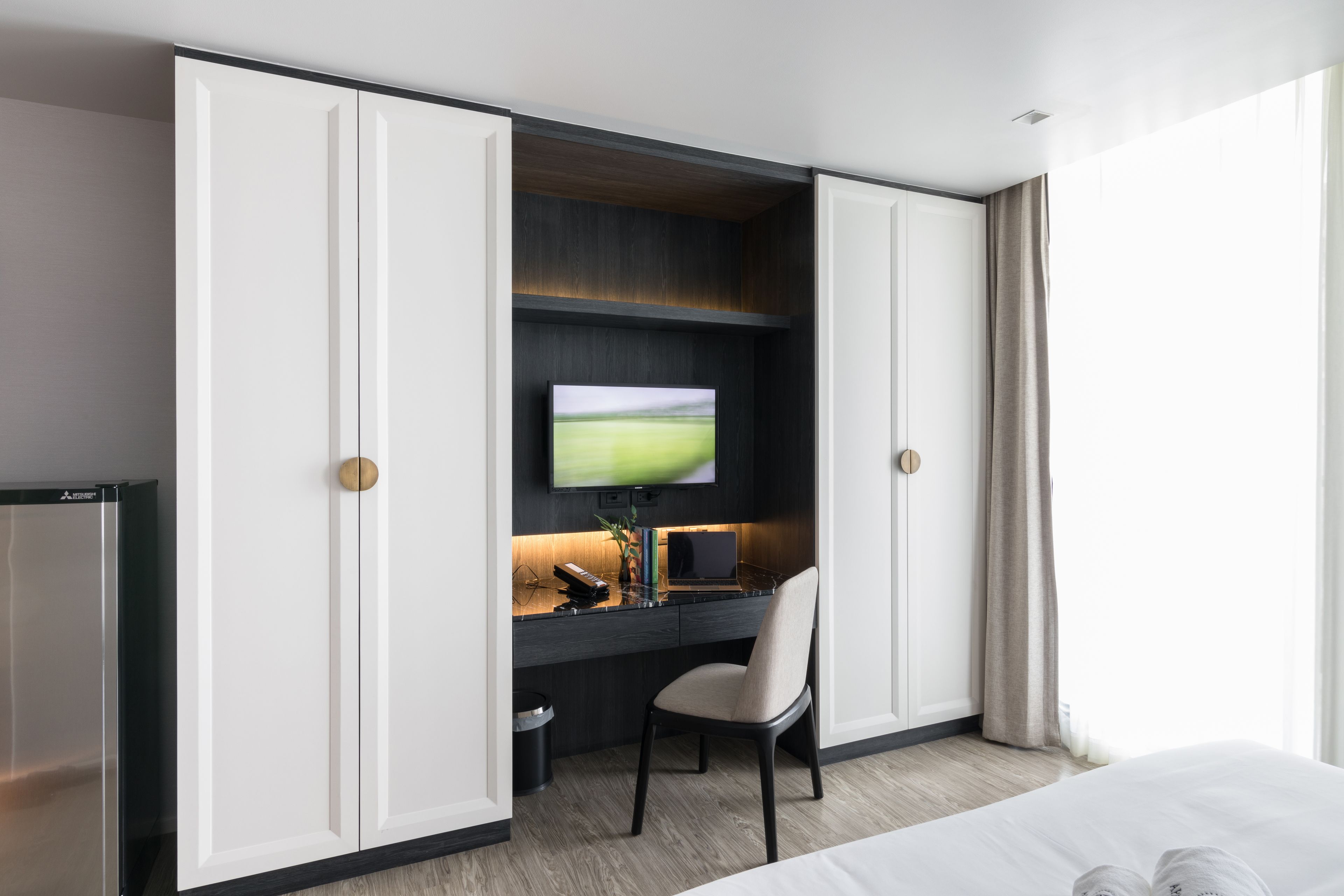 A hotel room with a large bed, a desk with a TV, and a wardrobe.