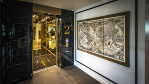 Un pasillo con piso de mármol negro, una puerta de vidrio con el número 2 y un gran mapa enmarcado en la pared.