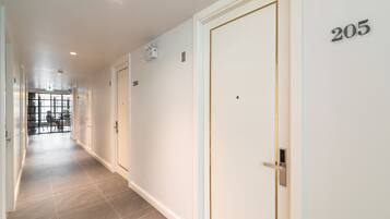 A corridor with a door marked 205, a security camera, and a glass door at the end.