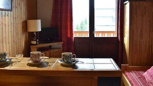 A wooden interior with a table set for tea, a television, and a wardrobe. - Cozy Studio for 4 Near Slopes and Shops in Méribel (Méribel)