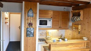 A kitchen with wooden cabinets, a microwave, and a sink. There is a wooden countertop with cups and a kettle. - Cozy Studio for 4 Near Slopes and Shops in Méribel (Méribel)