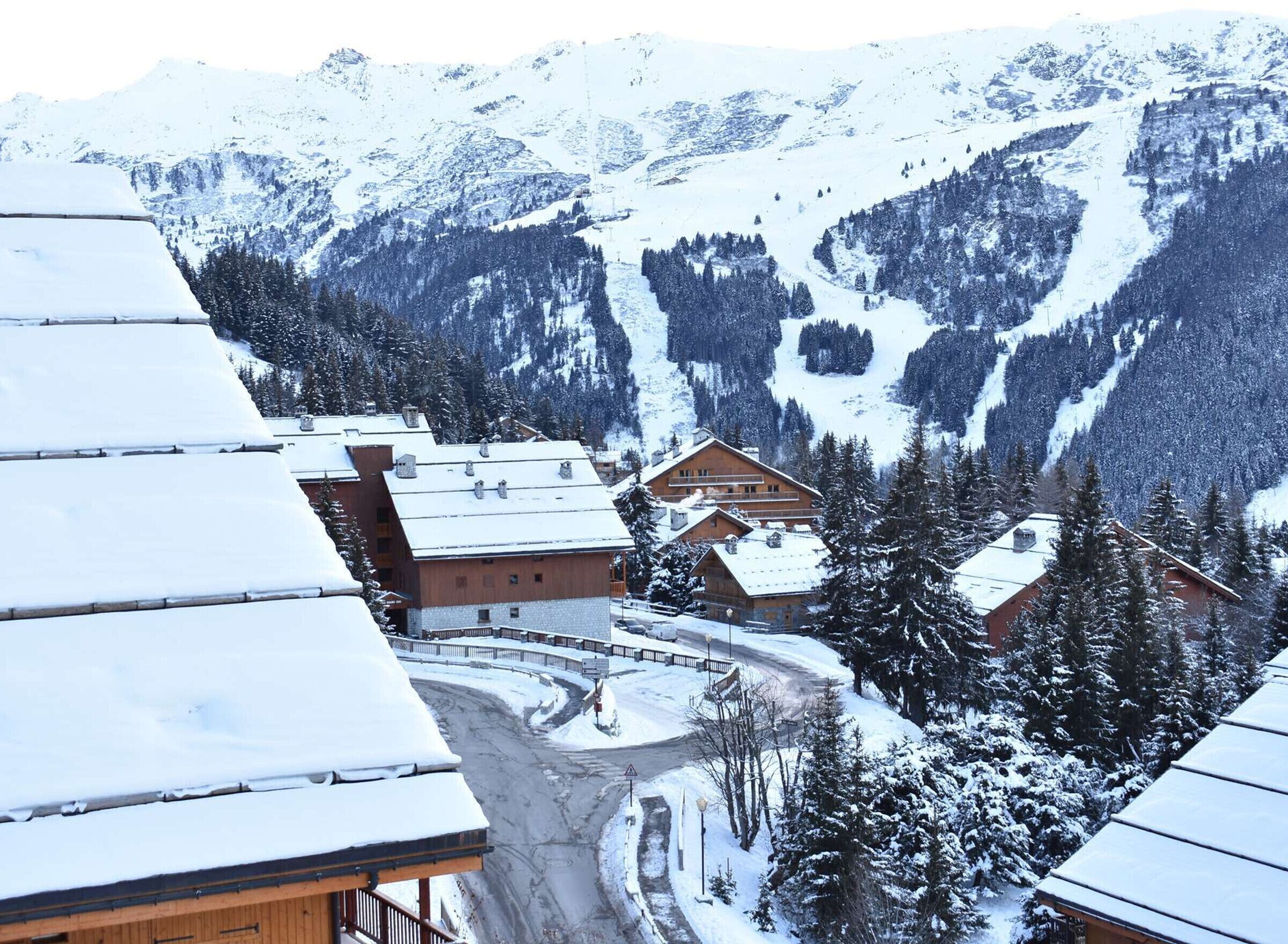 A snow-covered mountain village with wooden buildings and a winding road.