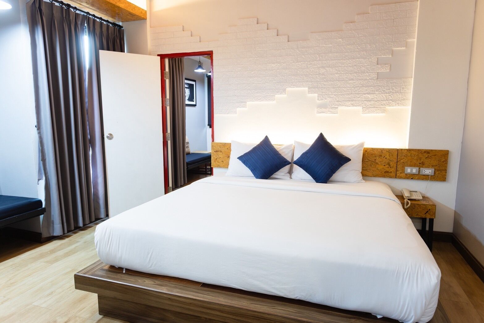 Una habitación de hotel con cama, mesita de noche y teléfono en la pared.