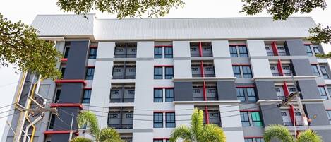 A multi-story building with a modern architectural design, featuring a grid of windows and balconies.