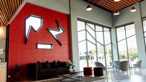 A modern interior with a red textured wall, a black sofa, and a glass partition. - PS Sriphu Hotel (Hat Yai)
