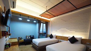A hotel room with two beds, a desk, a chair, and a large window with a view. - PS Sriphu Hotel (Hat Yai)