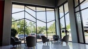 A modern interior with large windows, a glass coffee table, and seating. - PS Sriphu Hotel (Hat Yai)