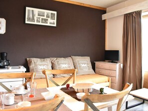 Quarto de hotel com cama, televisão, máquina de café e mesa de jantar com cadeiras.