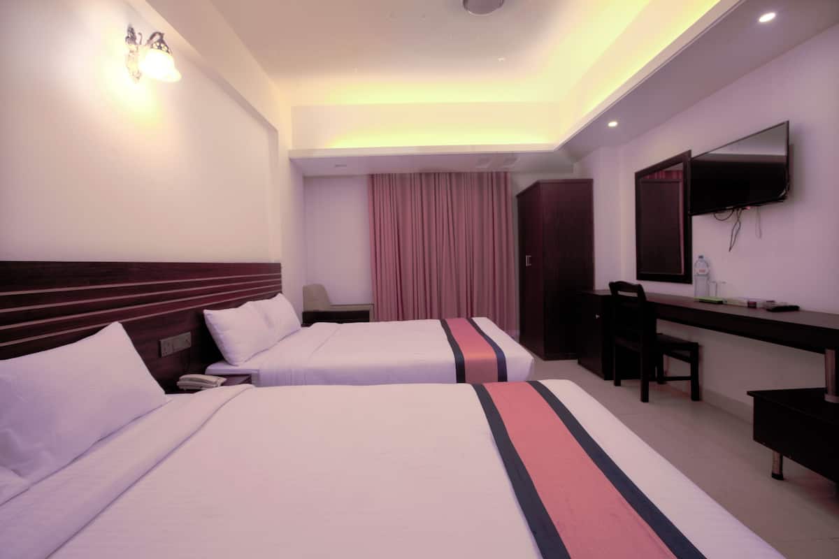 A hotel room with two beds, a desk, a chair, a mirror, and a television.