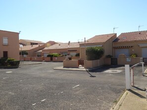 Houses with red-tiled roofs and gardens line the quiet street.