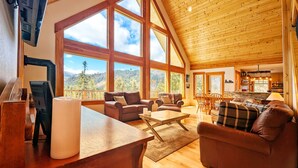 Amplia sala de estar con ventanas grandes, techo de madera y un rincón de asientos acogedor.