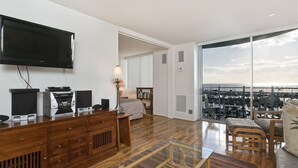 Ein modernes Wohnzimmer mit Flachbildfernseher, Holzmöbeln und einem großen Fenster mit Blick auf die Stadt.