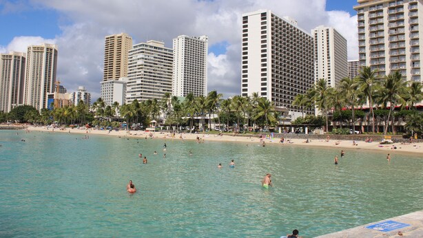 Ein Strandhotel mit mehreren Hochhäusern, einem Sandstrand und Palmen.