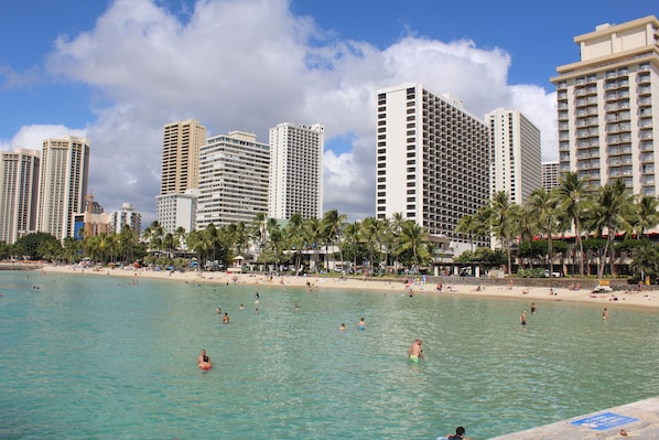 A beachfront hotel with multiple high-rise buildings, a sandy beach, and palm trees.