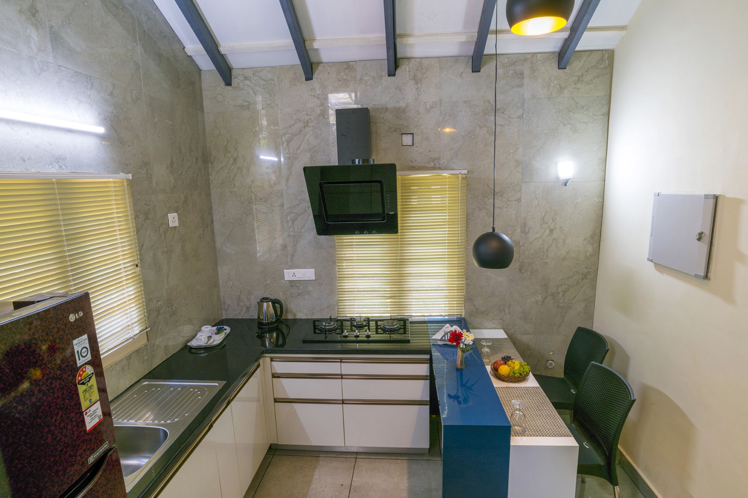 Una cocina compacta con estufa integrada, microondas y fregadero. Cuenta con un pequeño comedor con mesa y sillas.