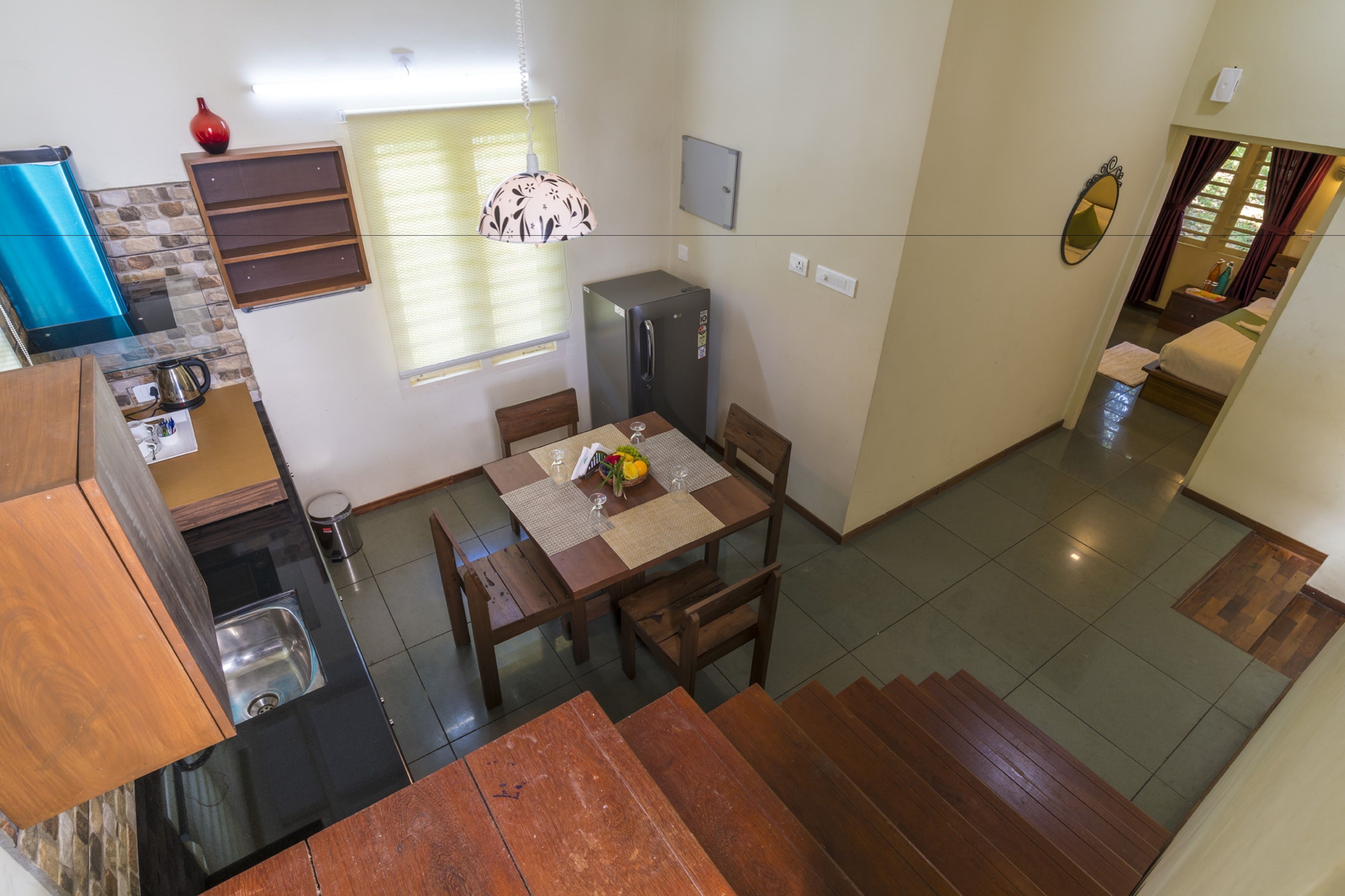 Cocina compacta con refrigerador, lavamanos y comedor con mesa y sillas.