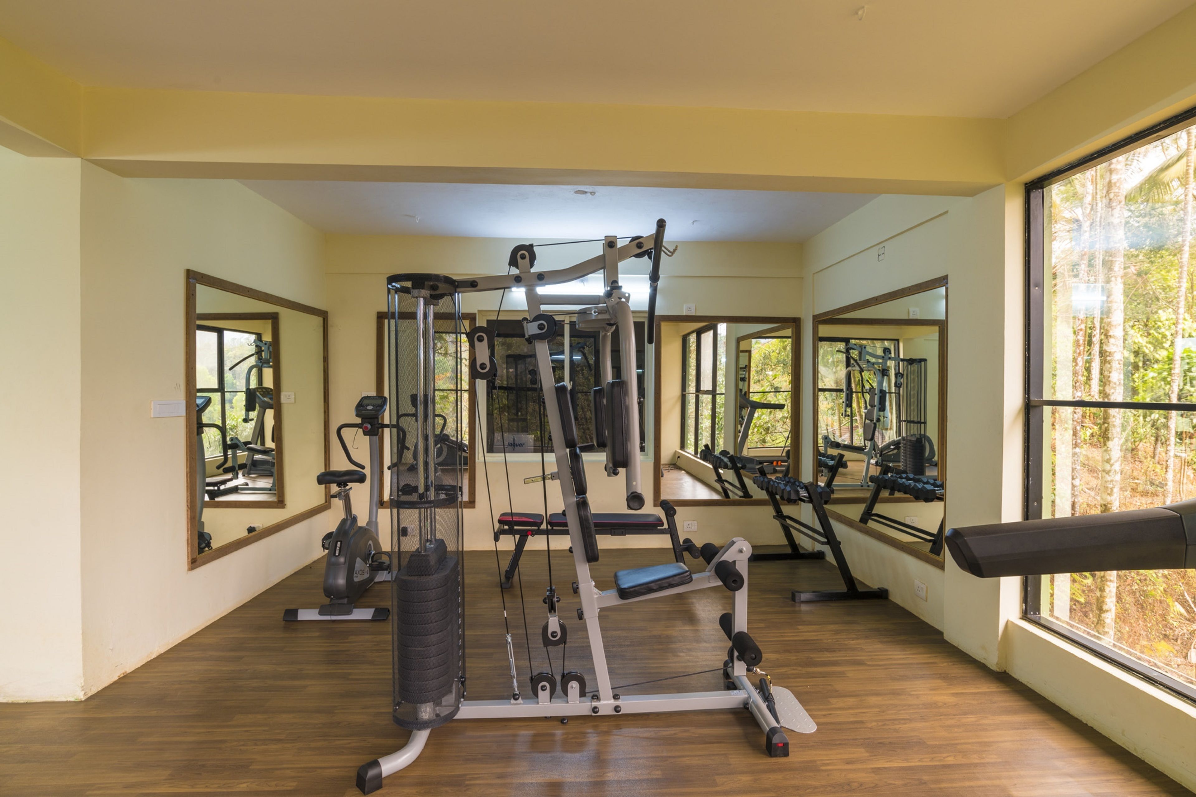A gym with exercise equipment, large windows, and wooden flooring.