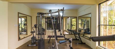 A gym with exercise equipment, large windows, and wooden flooring.