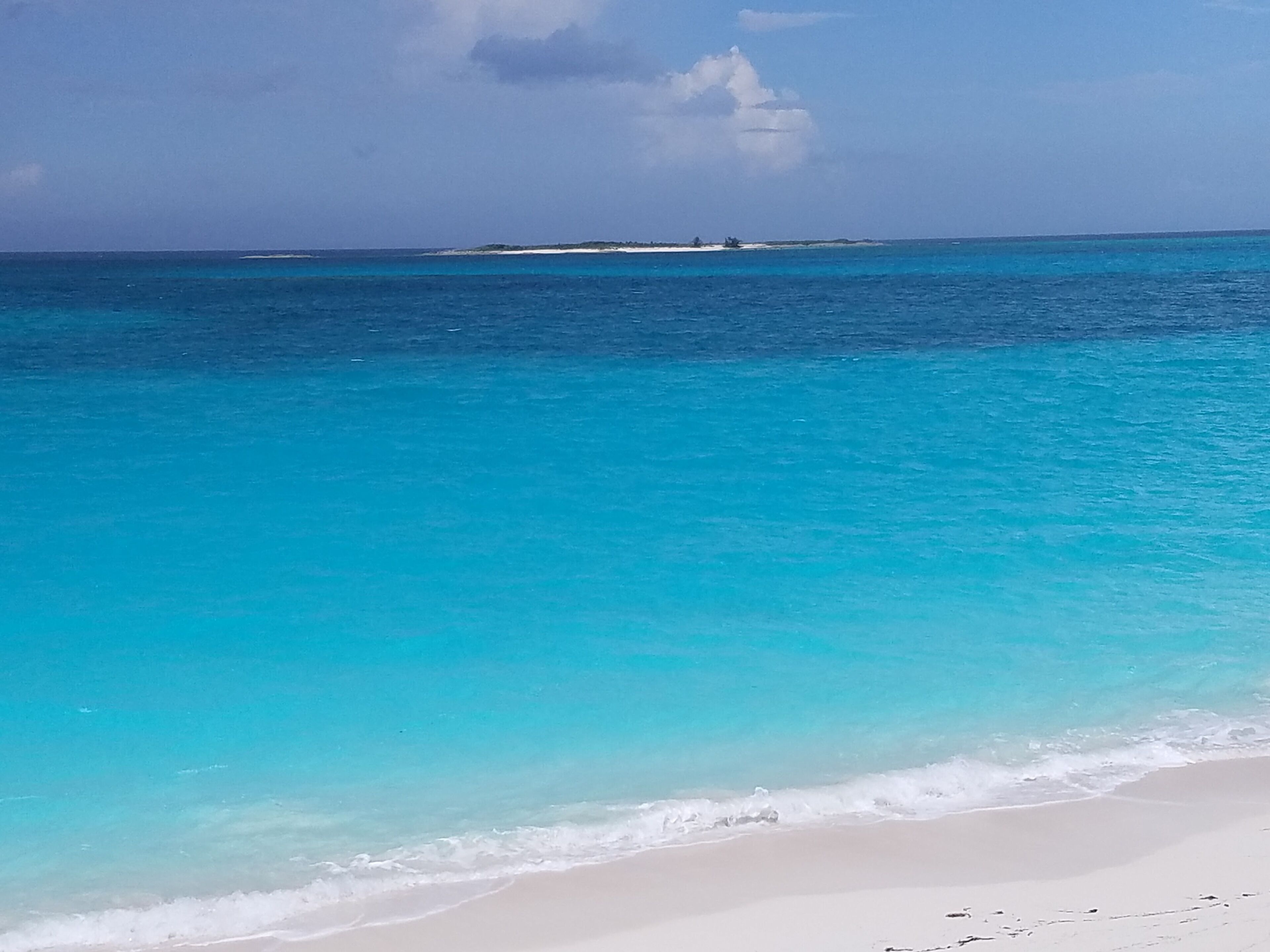 A beach with clear turquoise water and a sandy shore.