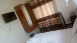 Ein Hotelzimmer mit Bett, Wandfernseher, Kleiderschrank und Vorhang.