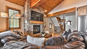 A cozy living room with leather sofas, a stone fireplace, and wooden beams. - Modern Mountain Luxury Home, Game Room! 8-Person Private Hot Tub (Park City)