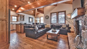 A spacious living area with a large leather sofa, a coffee table, and a stone fireplace. - Modern Mountain Luxury Home, Game Room! 8-Person Private Hot Tub (Park City)