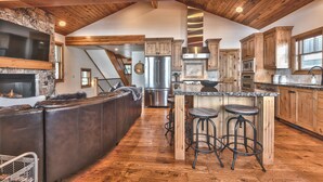 A spacious kitchen with a large island, wooden cabinets, and a stone fireplace. - Modern Mountain Luxury Home, Game Room! 8-Person Private Hot Tub (Park City)