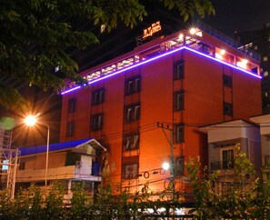 A multi-story building with a red facade, multiple windows, and a balcony with purple lighting. - Express Hostel (Bangkok)