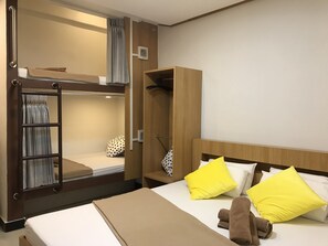 A hotel room with a bunk bed, a wardrobe, a bedside table, and a bed with yellow pillows. - Express Hostel (Bangkok)