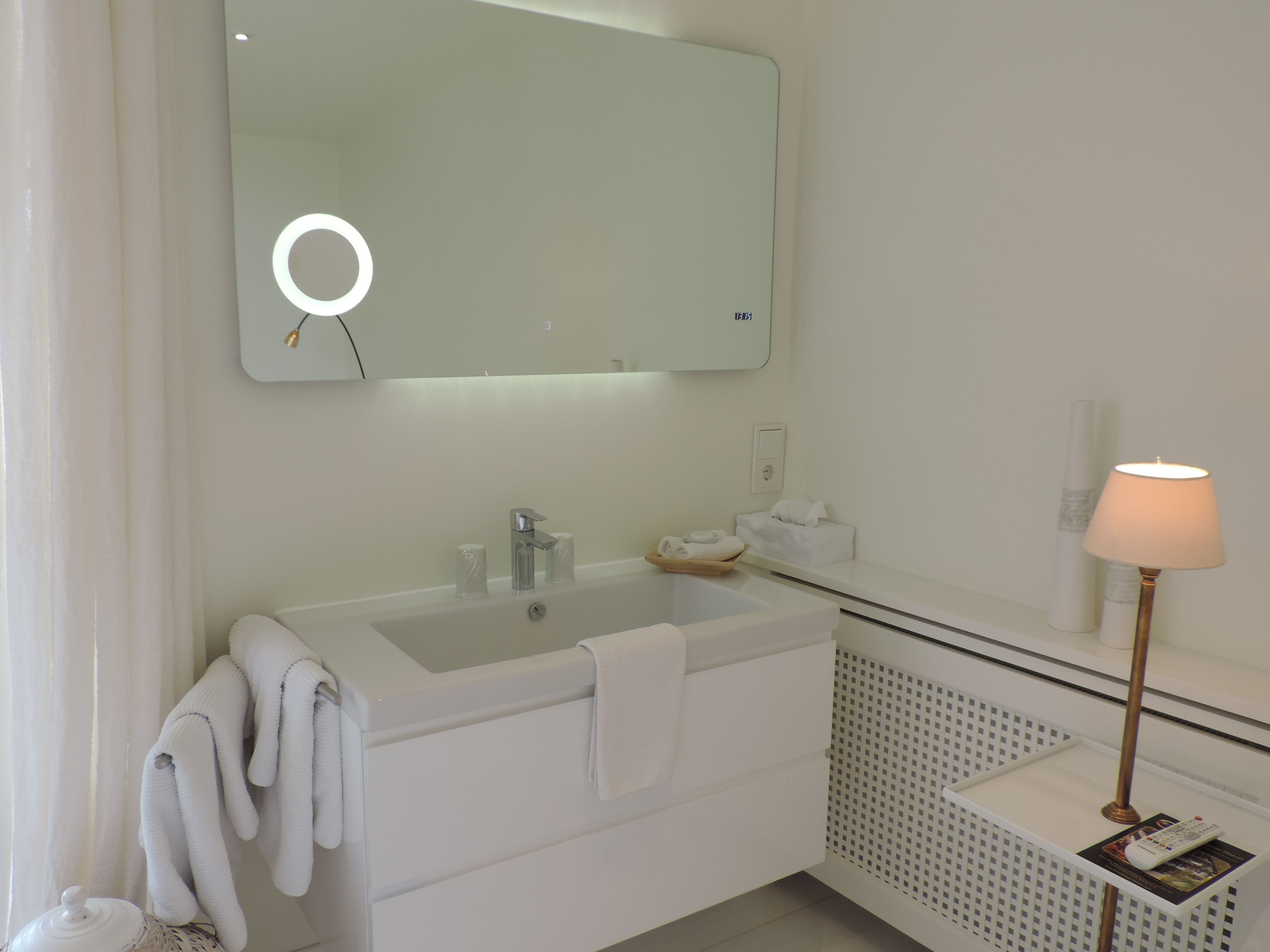 A modern bathroom with a large mirror, a sink, and a towel rack.