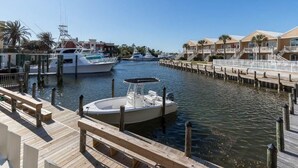 Un port de plaisance avec des bateaux amarrés, une jetée en bois et des bâtiments situés en bord de mer.