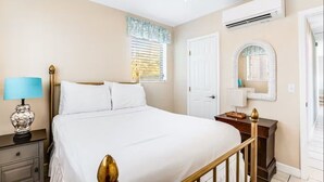 A bedroom with a bed, nightstand, lamp, and a ceiling fan. - Ground Level Home With Deepwater Canal And 30' Of Dock Space (Summerland Key)
