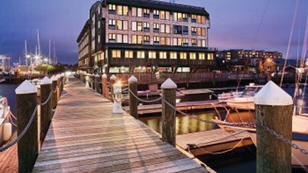 Hotel frente al agua con muelle de madera y barcos amarrados.