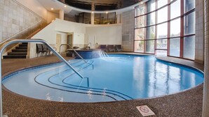 Una piscina interior con vista despejada a la escalera que lleva al nivel superior, una zona de estar con sillas y un letrero que indica que no se permite bucear en el borde de la piscina.