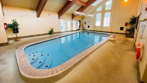 Ein Hallenbad mit freiem Blick auf Deckenbalken, Fenster und einen Rettungsschwimmerstuhl.